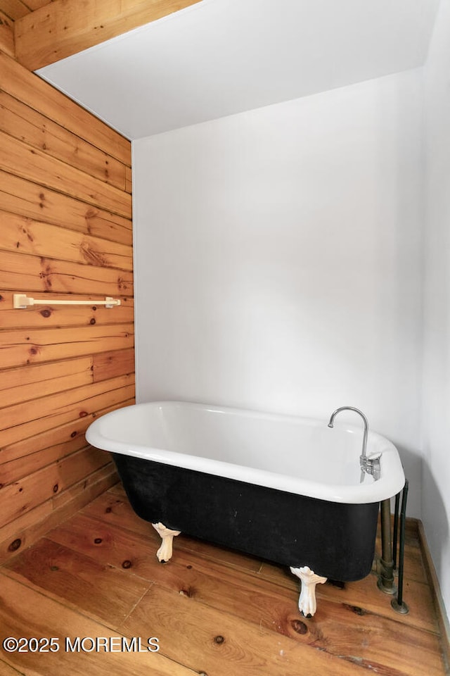 bathroom with wood-type flooring, a bathtub, and wood walls