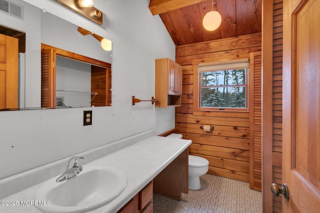 bathroom with vanity, wooden walls, vaulted ceiling with beams, toilet, and wood ceiling