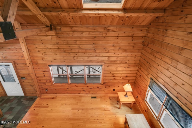 interior space featuring beamed ceiling, a skylight, wooden walls, and wooden ceiling