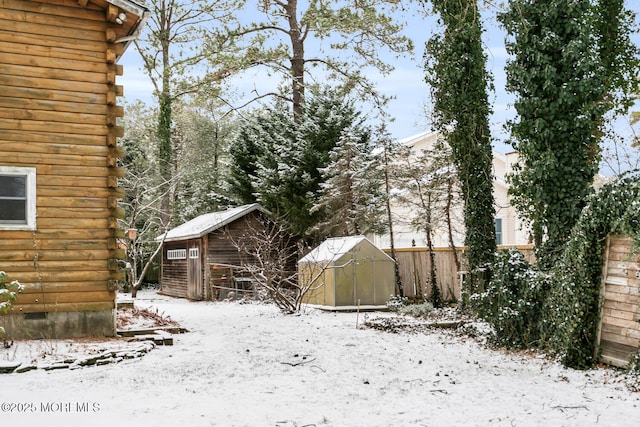 yard layered in snow featuring a storage shed