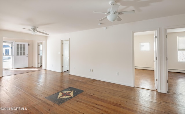 unfurnished living room featuring ceiling fan, wood-type flooring, and a baseboard heating unit