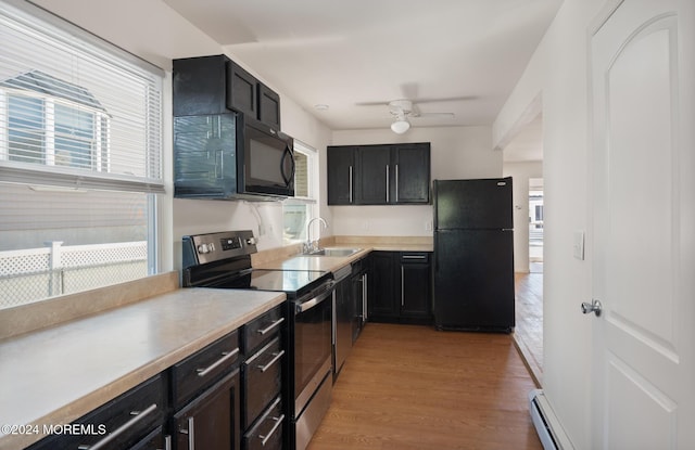 kitchen with ceiling fan, sink, a baseboard radiator, black appliances, and light wood-type flooring