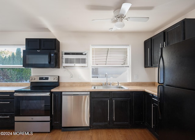 kitchen with a wall mounted AC, ceiling fan, sink, black appliances, and light hardwood / wood-style flooring