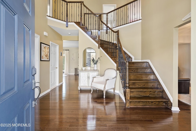 entryway with stairs, a high ceiling, wood finished floors, and baseboards