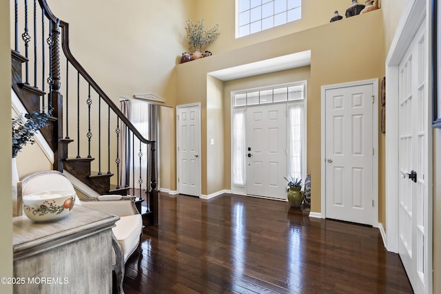 foyer featuring a towering ceiling and dark wood-type flooring