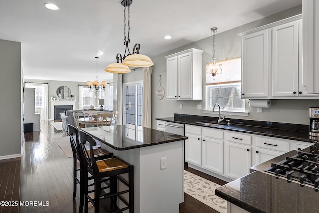 kitchen with a kitchen island, a sink, white cabinets, open floor plan, and dark wood finished floors