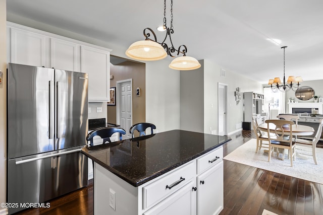 kitchen featuring white cabinets, a center island, stainless steel fridge, and dark stone counters