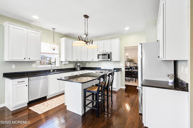 kitchen featuring appliances with stainless steel finishes, dark wood-style flooring, a sink, and a kitchen island