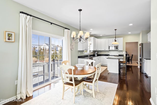 dining space with dark hardwood / wood-style flooring, sink, and an inviting chandelier