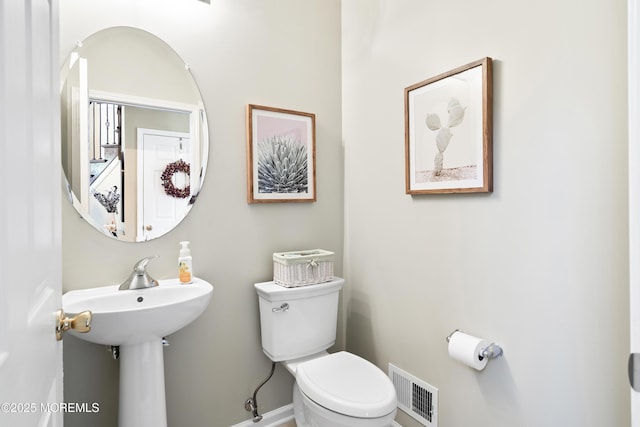 half bath with baseboards, visible vents, and toilet