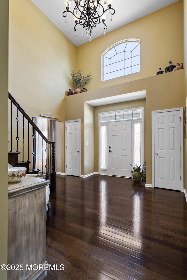 foyer with a notable chandelier, dark hardwood / wood-style floors, and a towering ceiling