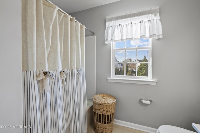 bathroom with a tub to relax in, tile patterned flooring, toilet, baseboards, and a shower with curtain