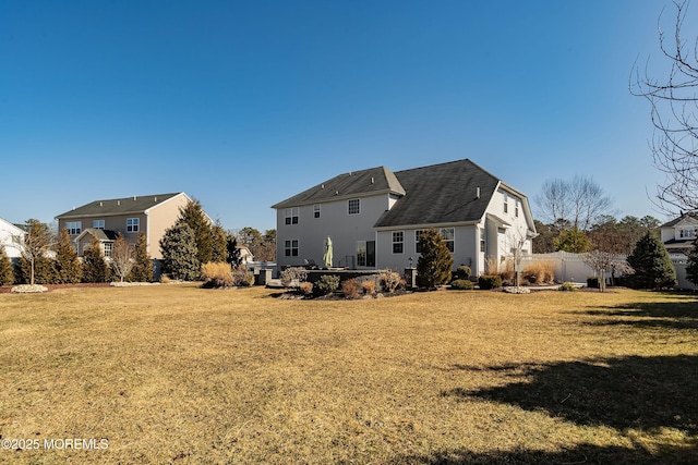 rear view of house featuring a yard and fence