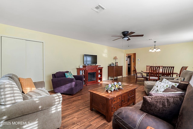 living room featuring dark wood-type flooring and ceiling fan with notable chandelier