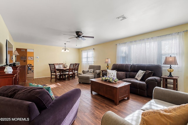 living room featuring ceiling fan with notable chandelier and dark hardwood / wood-style flooring