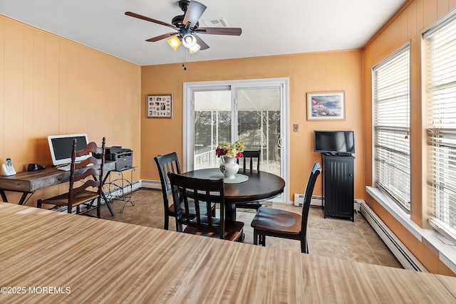 tiled dining area featuring ceiling fan, baseboard heating, and wood walls