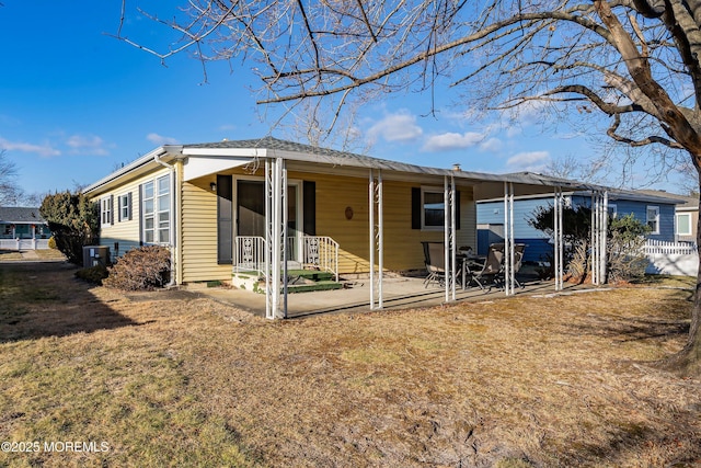 rear view of house with a lawn and a patio