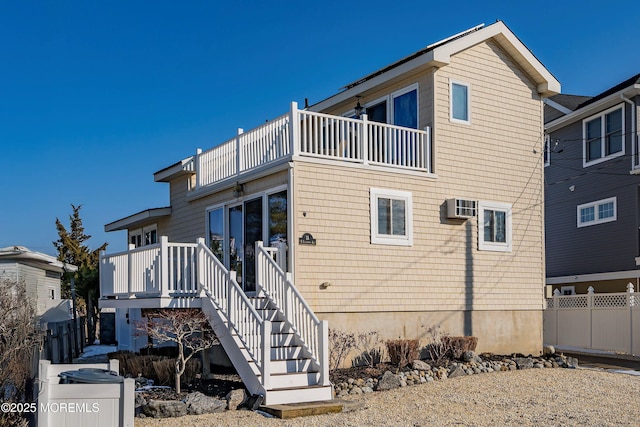 rear view of house featuring an AC wall unit and a balcony