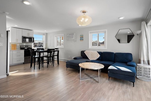 living room with a wall mounted AC, light wood-type flooring, and baseboard heating