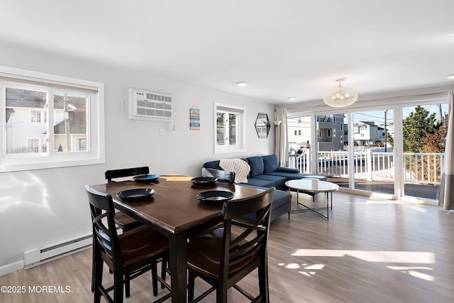 dining room featuring an AC wall unit, a baseboard heating unit, and hardwood / wood-style flooring