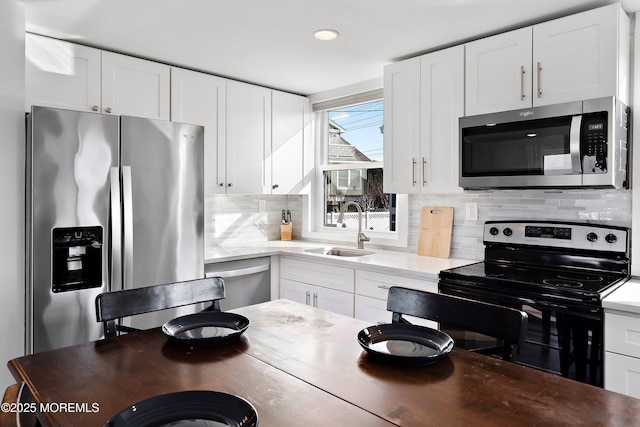 kitchen with sink, stainless steel appliances, white cabinetry, and backsplash