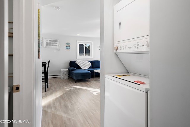 laundry area with stacked washing maching and dryer, baseboard heating, light wood-type flooring, and a wall mounted air conditioner