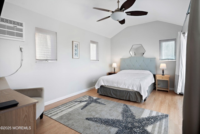 bedroom featuring lofted ceiling, an AC wall unit, light wood-type flooring, and ceiling fan