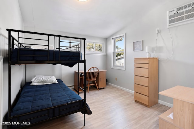 bedroom with hardwood / wood-style flooring, a baseboard radiator, vaulted ceiling, and a wall mounted AC