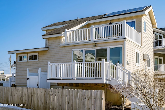 rear view of property with a balcony and an AC wall unit