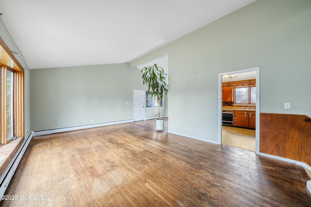 spare room with a healthy amount of sunlight, beverage cooler, vaulted ceiling, and hardwood / wood-style flooring