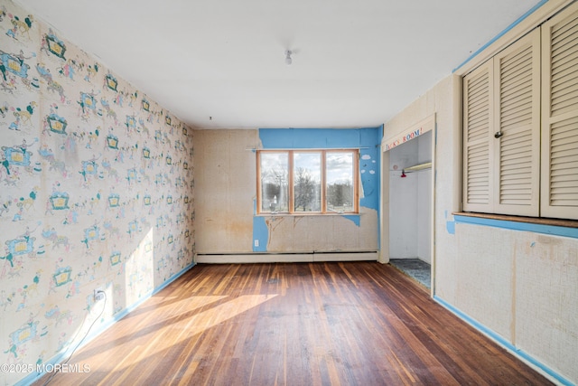 empty room featuring wood-type flooring and baseboard heating