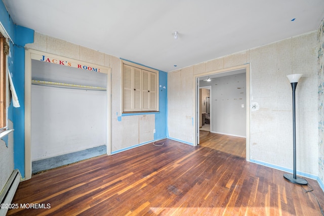 unfurnished bedroom with a baseboard radiator, a closet, and dark wood-type flooring