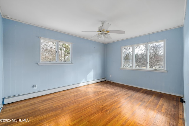 spare room featuring wood-type flooring, a baseboard radiator, a wealth of natural light, and ceiling fan