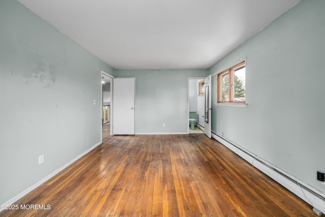 empty room with dark wood-type flooring and a baseboard heating unit