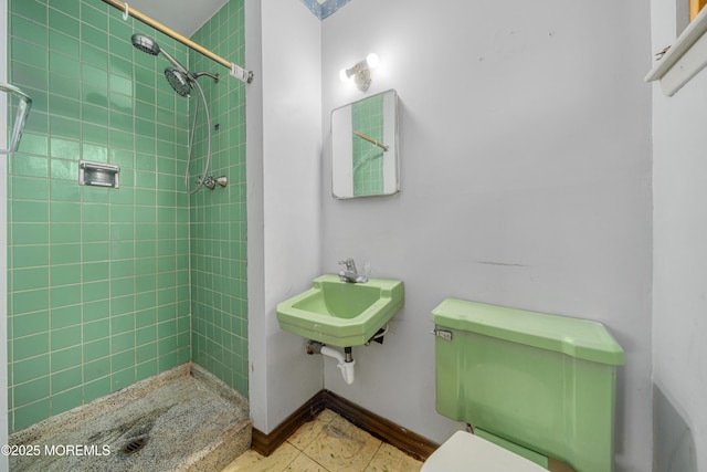 bathroom with a tile shower, sink, and toilet