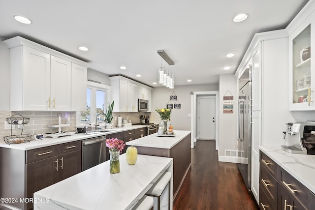 kitchen with sink, stainless steel appliances, tasteful backsplash, decorative light fixtures, and a kitchen island