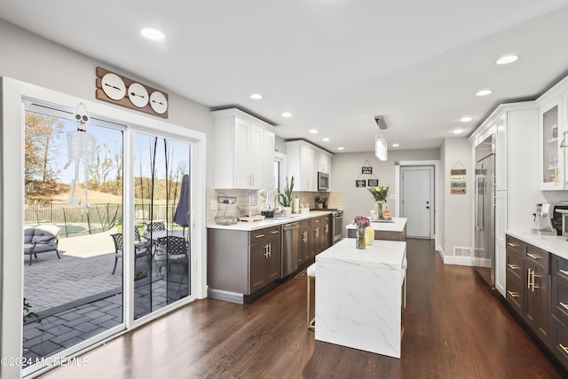 kitchen with white cabinets, dark hardwood / wood-style flooring, stainless steel appliances, and tasteful backsplash