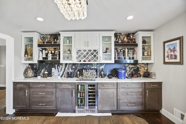 bar with backsplash, white cabinetry, beverage cooler, and dark wood-type flooring