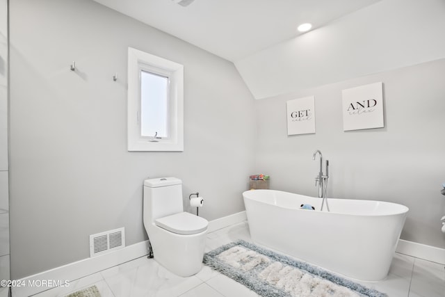 bathroom with a bathing tub, vaulted ceiling, and toilet