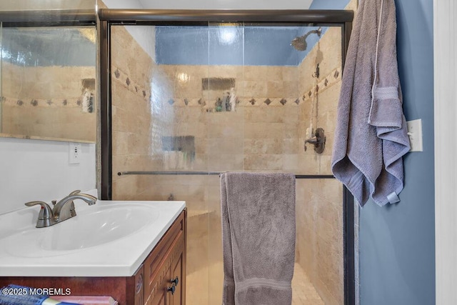 bathroom featuring a shower with shower door and vanity