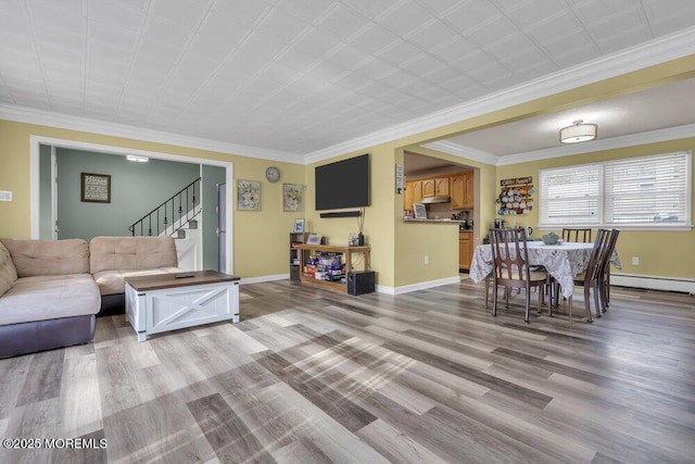 living room with baseboard heating, crown molding, and light hardwood / wood-style floors