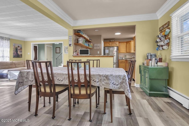 dining space featuring light wood-type flooring, baseboard heating, and crown molding