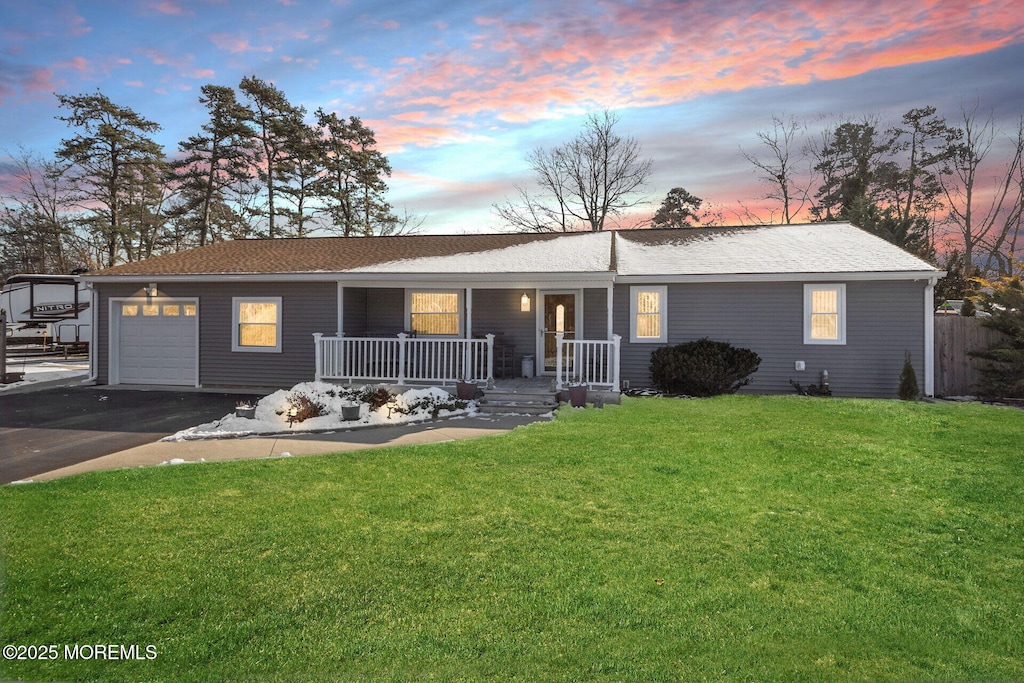 ranch-style home with a lawn, a porch, and a garage