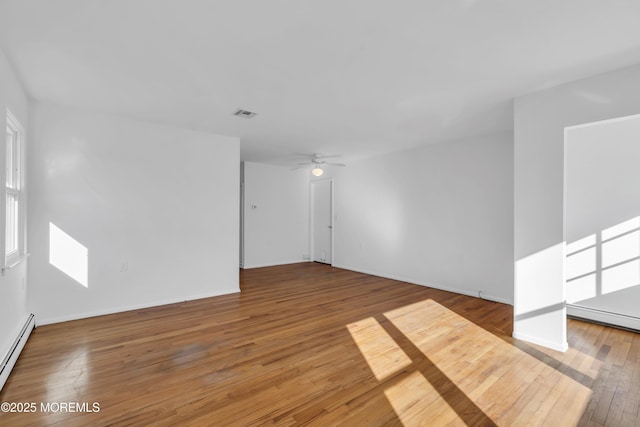 empty room with ceiling fan, hardwood / wood-style floors, and a baseboard heating unit