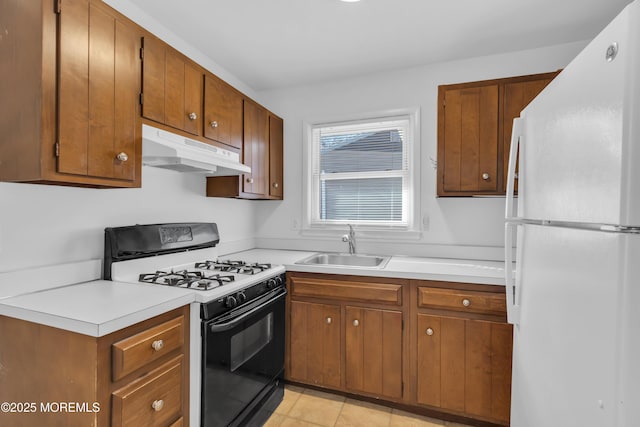 kitchen featuring gas range, sink, light tile patterned floors, and white refrigerator