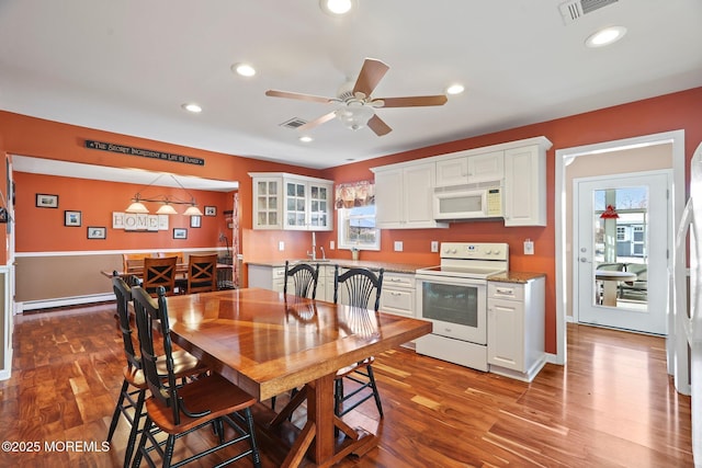 kitchen with white appliances, ceiling fan, white cabinetry, and a baseboard radiator