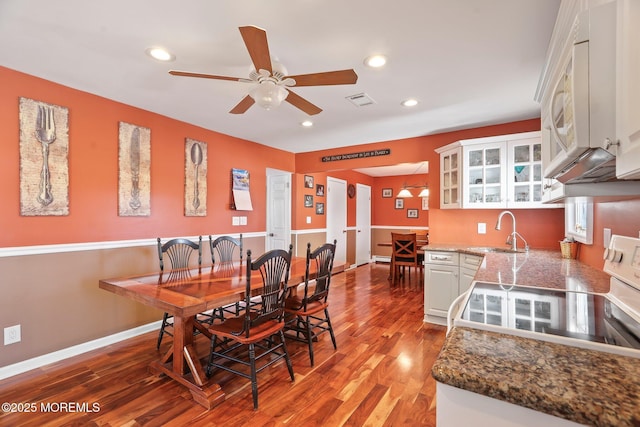 dining area with ceiling fan, sink, and wood-type flooring