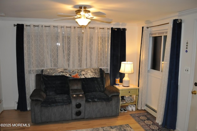 living room featuring ceiling fan, crown molding, wood-type flooring, and a baseboard radiator