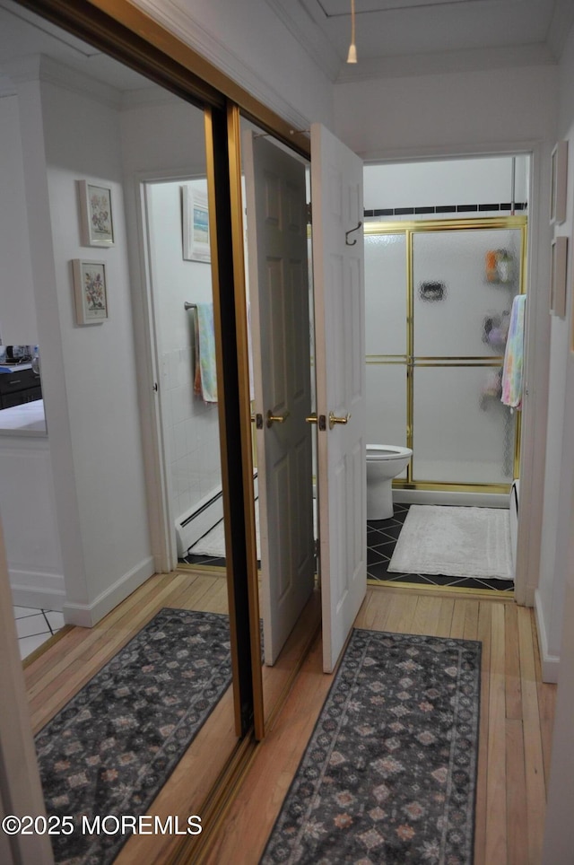 bathroom featuring an enclosed shower, ornamental molding, a baseboard radiator, hardwood / wood-style floors, and toilet