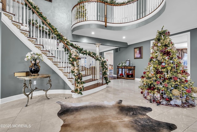 foyer with a towering ceiling, decorative columns, and ornamental molding